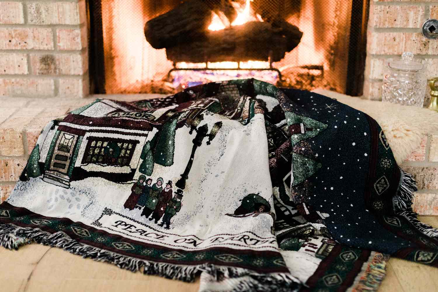 Una alfombra navideña en el suelo frente a una chimenea encendida
