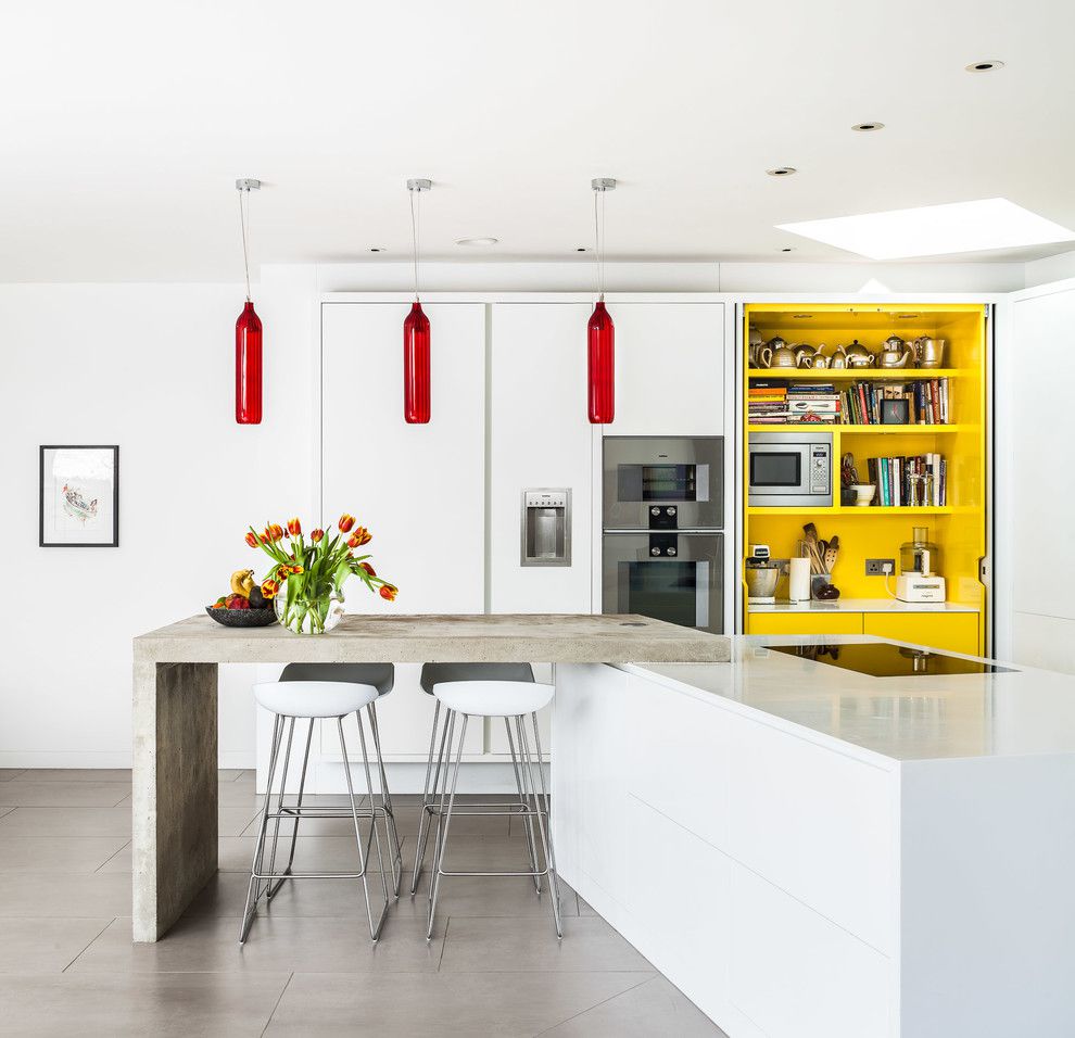 estanterías empotradas amarillas en una moderna cocina blanca con mostradores de hormigón