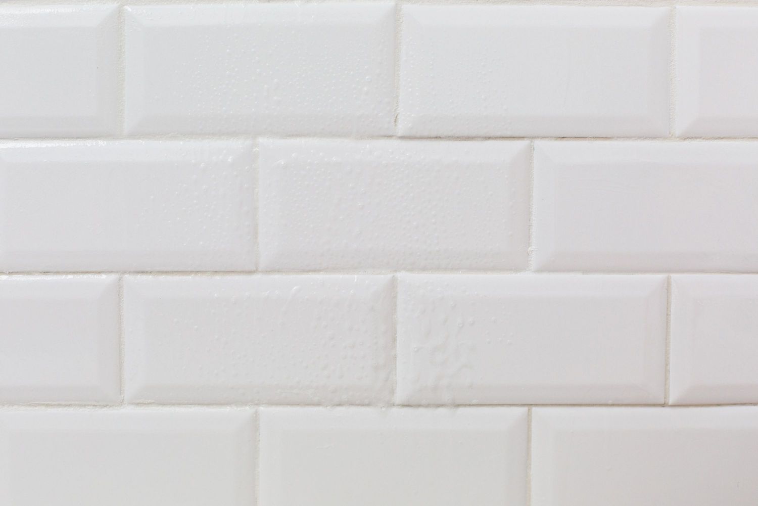 Una pared de azulejos blancos con una solución de limpieza rociada sobre ella 