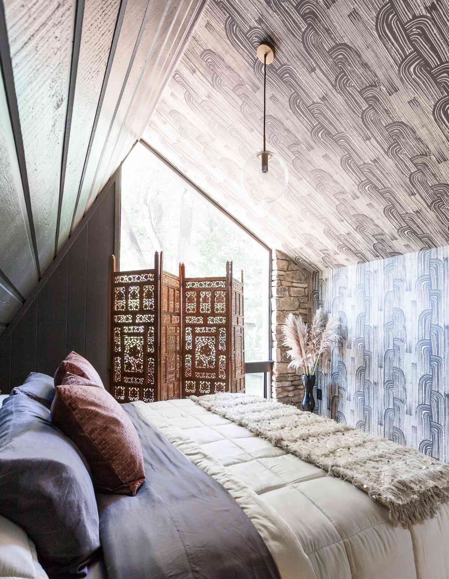 una habitación pequeña con papel tapiz y ropa de cama estampados en gris