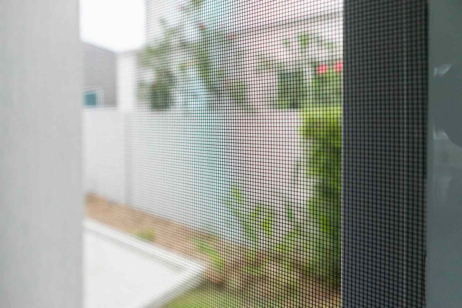 Una pantalla de alta calidad sin agujeros, colocada sobre una ventana para evitar que moscas, mosquitos y otras plagas voladoras entren en la casa.